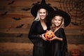 Halloween Concept - beautiful caucasian mother and her daughter in witch costumes celebrating Halloween with sharing Halloween can Royalty Free Stock Photo