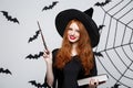 Halloween Concept - Beautiful Witch playing with magic stick on grey background. Royalty Free Stock Photo