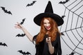 Halloween Concept - Beautiful Witch playing with magic stick on grey background. Royalty Free Stock Photo