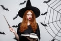 Halloween Concept - Beautiful Witch playing with magic stick on grey background. Royalty Free Stock Photo