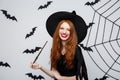 Halloween Concept - Beautiful Witch playing with magic stick on grey background. Royalty Free Stock Photo