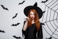 Halloween Concept - Beautiful Witch playing with magic stick on grey background. Royalty Free Stock Photo