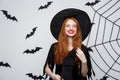 Halloween Concept - Beautiful Witch playing with magic stick on grey background. Royalty Free Stock Photo