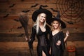 Halloween Concept - cheerful mother and her daughter in witch costumes celebrating Halloween posing with curved pumpkins over bats Royalty Free Stock Photo