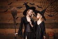 Halloween Concept - cheerful mother and her daughter in witch costumes celebrating Halloween posing with curved pumpkins over bats Royalty Free Stock Photo