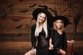 Halloween Concept - cheerful mother and her daughter in witch costumes celebrating Halloween posing with curved pumpkins over bats Royalty Free Stock Photo