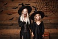 Halloween Concept - cheerful mother and her daughter in witch costumes shocking with something.