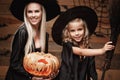 Halloween Concept - Closeup beautiful caucasian mother and her daughter in witch costumes celebrating Halloween posing with curved