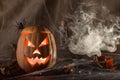 The ghastly, ghastly pumpkin glows with a fiery yellow light smoke and autumn leaves Royalty Free Stock Photo
