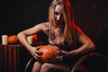 Halloween concept, girl vampire with red eyes red lips sit on rocking chair with pumpkins around. Scary woman trick or treat time Royalty Free Stock Photo