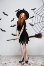Halloween Concept - Happy elegant witch enjoy playing with broomstick halloween party over grey background.
