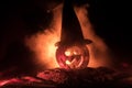 Halloween concept. Jack-o-lantern smile and scary eyes for party night. Close up view of scary pumpkin with witch hat on at dark f Royalty Free Stock Photo