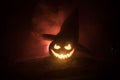 Halloween concept. Jack-o-lantern smile and scary eyes for party night. Close up view of scary pumpkin with witch hat on at dark f Royalty Free Stock Photo