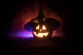 Halloween concept. Jack-o-lantern smile and scary eyes for party night. Close up view of scary pumpkin with witch hat on at dark f Royalty Free Stock Photo