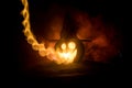 Halloween concept. Jack-o-lantern smile and scary eyes for party night. Close up view of scary pumpkin with witch hat on at dark f Royalty Free Stock Photo