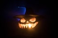 Halloween concept. Jack-o-lantern smile and scary eyes for party night. Close up view of scary pumpkin with witch hat on at dark f Royalty Free Stock Photo