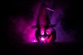 Halloween concept. Jack-o-lantern smile and scary eyes for party night. Close up view of scary pumpkin with witch hat on at dark f Royalty Free Stock Photo