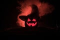 Halloween concept. Jack-o-lantern smile and scary eyes for party night. Close up view of scary pumpkin with witch hat on at dark Royalty Free Stock Photo