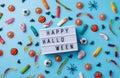 Halloween holiday decorations and sweets with lightbox with words Happy Halloween flat lay on blue background