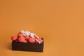 Halloween concept, skeleton sleeping on wooden box with marshmallow pumpkins on orange background Royalty Free Stock Photo