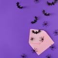 Halloween concept with spiders, bats and paper envelope on purple background with copy space.