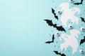 Halloween concept. Top view photo of ghost bat silhouettes spooky eyes and black confetti on isolated pastel blue background with