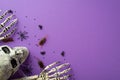 Halloween concept. Top view photo of skull skeleton hands spiderweb spiders cockroaches centipedes and confetti on isolated violet