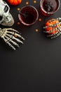 Halloween concept. Top view vertical photo of blood punch in glasses with floating spiders straws skull skeleton hands holding