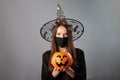 Halloween in covid,witch in a mask with a pumpkin with sweets,safety and health care at parties on the eve of all saints,girl in a