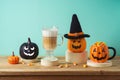 Halloween creative concept with latte macchiato coffee cup, candy corn and jack o lantern pumpkin decor on wooden table