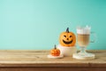 Halloween creative concept with latte macchiato coffee cup and pumpkin decor on wooden table