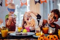 Emotional funny children wearing different Halloween costumes taking cupcakes