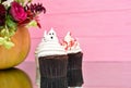 Halloween cupcakes. Spooky ghost bloody cupcakes. Halloween treats on pink wood background. Halloween pumpkin with flowers