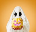 Halloween cute ghost holding glowing jack-o-lantern pumpkin.