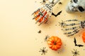 Halloween decor concept. Top view photo of scary skull skeleton hands holding pumpkins spiders bat silhouettes and confetti on