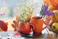 Halloween decor, a couple of cups with a drink, spiders, pumpkins, fruits, leaves on the windowsill, autumn seasonal holidays