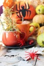 Halloween decor, a couple of cups with a drink, spiders, pumpkins, fruits, leaves on the windowsill, autumn seasonal holidays