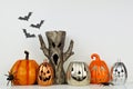 Halloween decor with jack o lantern and spooky tree against a white wall