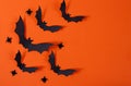 Halloween decor with spiders and black paper bats flying over orange background