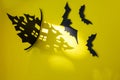 Halloween and decoration concept - bats, pumpkins, gloomy paper house, gloomy black tree branches on a yellow background. Royalty Free Stock Photo