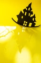 Halloween and decoration concept - bats, pumpkins, gloomy paper house, gloomy black tree branches on a yellow background. Royalty Free Stock Photo