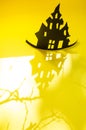 Halloween and decoration concept - bats, pumpkins, gloomy paper house, gloomy black tree branches on a yellow background. Royalty Free Stock Photo