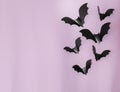 Halloween, decoration and scary concept - black bats flying over lilac background