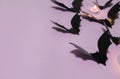 Halloween, decoration and scary concept - black bats flying over lilac background