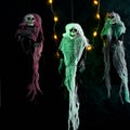 Halloween decoration three skeletons in a multicolored cape decorated with a garland of glowing pumpkins