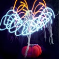 Halloween decoration three skeletons in a multicolored cape decorated with a garland of glowing pumpkins and spiders. The light of