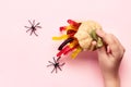 Halloween decorations. Children`s hand opens pumpkin with treat of marmalade worms and spiders