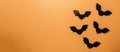 Halloween decorations concept. Black paper bats on orange background. Top view Copy space Horizontal banner Royalty Free Stock Photo