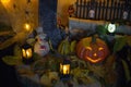 Halloween decorations concept at night. Close up of jack o`lantern, vintage lanterns, pumpkins, skull, autumn leaves