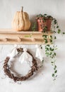 Halloween decorations. Homemade paper ghosts garland, grape wreath, pumpkin on a wooden hanger in the hallway